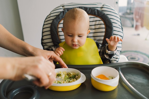 Foto niña pequeña con nutrición sólida niña comiendo comida y mezclando plato de verduras