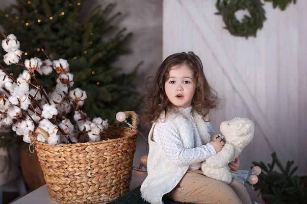 Niña pequeña con osito de peluche en Navidad