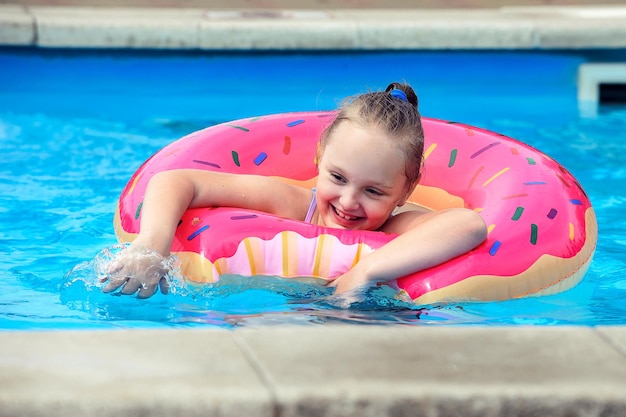 una niña pequeña pasa sus vacaciones en una piscina al aire libre con agua fresca en verano
