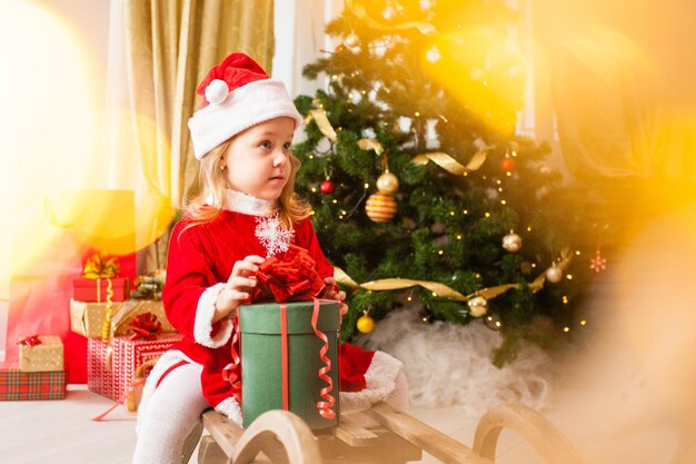 Niña pequeña pide un deseo y sueña cerca del árbol de Navidad Hora mágica de la víspera de Navidad