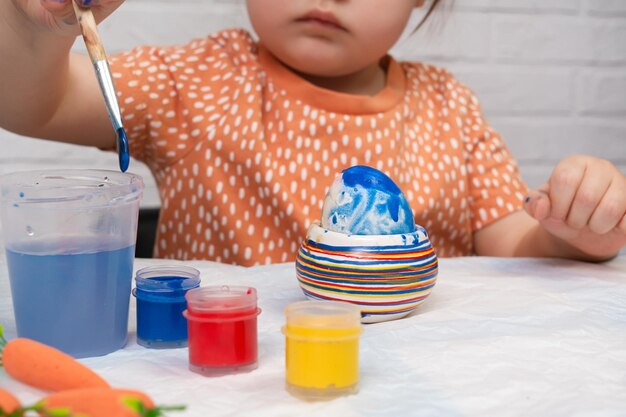 Una niña pequeña pinta huevos de Pascua Preparación para las vacaciones de Pascua Feliz Pascua de cerca