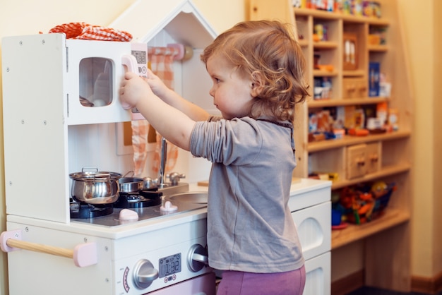 Niña pequeña que juega la cocina del juguete