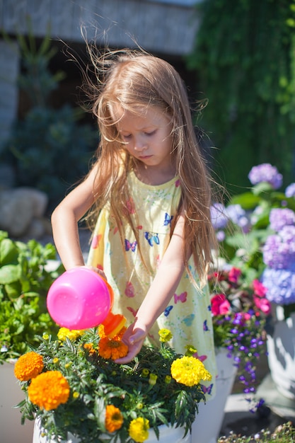 Niña pequeña regando flores con una regadera