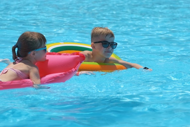 Niña pequeña relajándose en el sol de verano nadando en un colchón de aire inflable en la piscina durante las vacaciones tropicales Concepto de actividades de verano