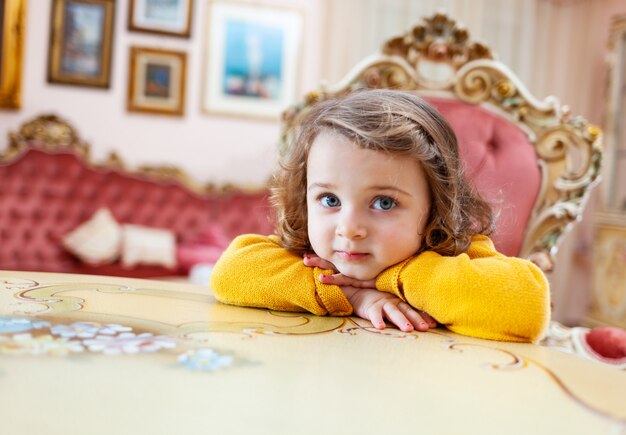 Niña pequeña en una sala de estar con decoración barroca.