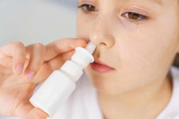 Niña pequeña con secreción nasal se irriga con aerosol nasal para detener la rinitis alérgica y la sinusitis