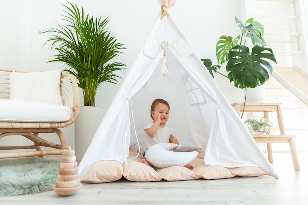 Niña pequeña sentada en un wigwam en casa