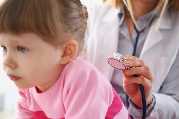 Niña pequeña siendo examinada por un pediatra, una niña tranquila esperando pacientemente una cita