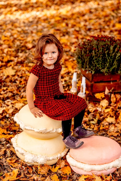 La niña pequeña se sienta en los dulces macarrones