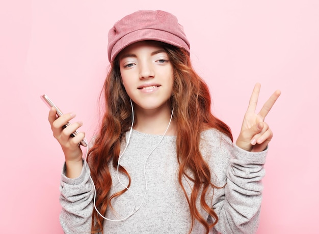 Niña pequeña con smartphone sobre fondo rosa de cerca