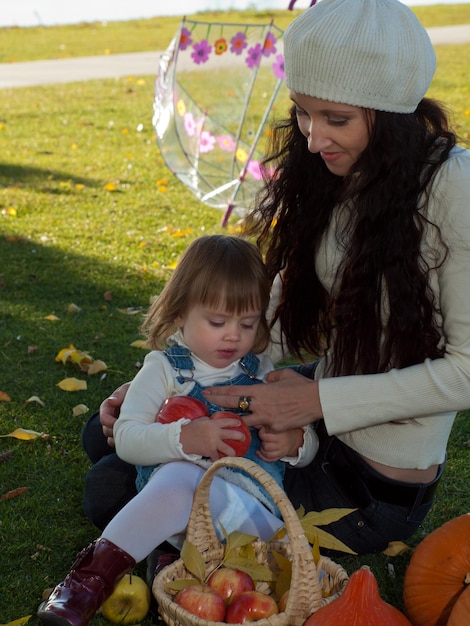 Niña pequeña con su madre en el parque otoño.