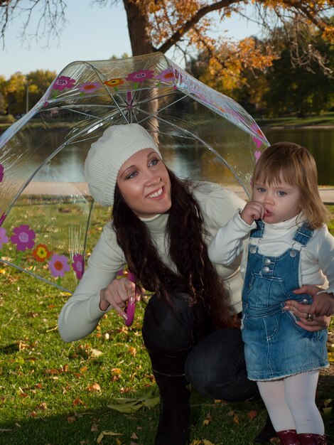 Niña pequeña con su madre en el parque otoño.