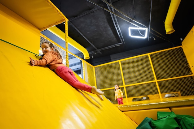 Niña pequeña tobogán en el parque infantil amarillo