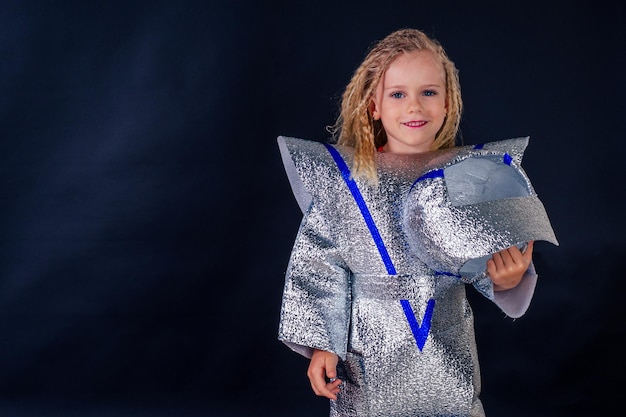 Niña pequeña con traje espacial diy de aluminio sobre un fondo negro en el estudio 20 de julio de 1969 día de aterrizaje en la luna niño soñando futura profesión 12 de abril