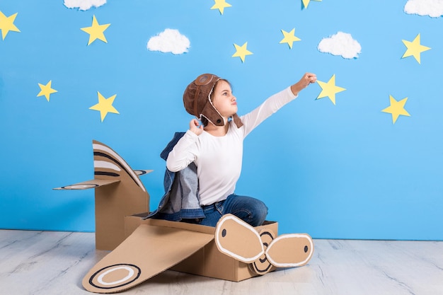 Foto niña pequeña en traje de piloto está jugando y soñando con volar sobre las nubes.