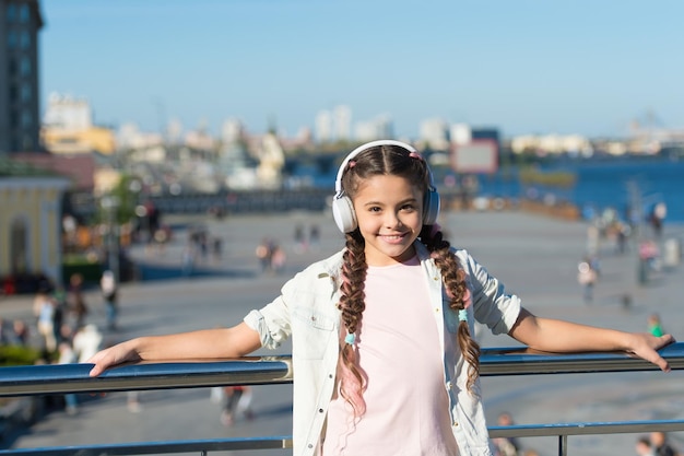 Niña pequeña turista explora la ciudad usando la aplicación de audioguía Estilo libre de viajar Emocionantes viajes a través de ciudades y museos Aparato de audio para auriculares Guía de la ciudad y audioguía