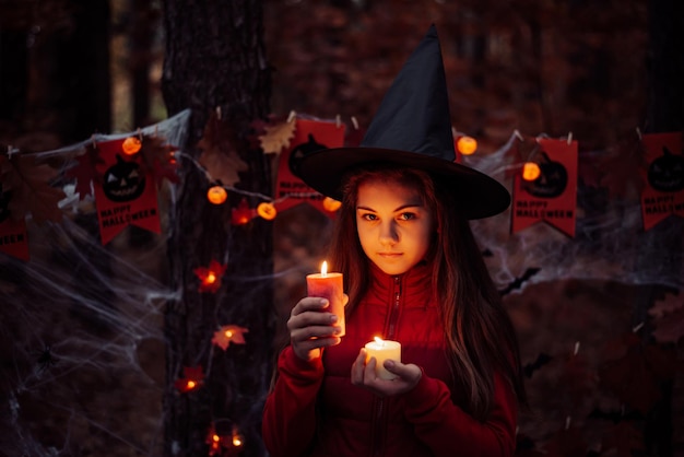 Niña pequeña con velas encendidas en el bosque oscuro