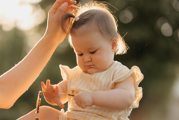 Una niña pequeña vestida de amarillo está jugando con gafas de sol en el parque