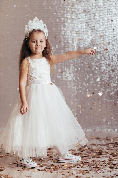 Niña pequeña con vestido de princesa sobre fondo de confeti