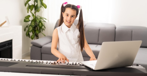 Niña pequeña viendo un tutorial de lecciones en línea sobre cómo aprender un sintetizador.