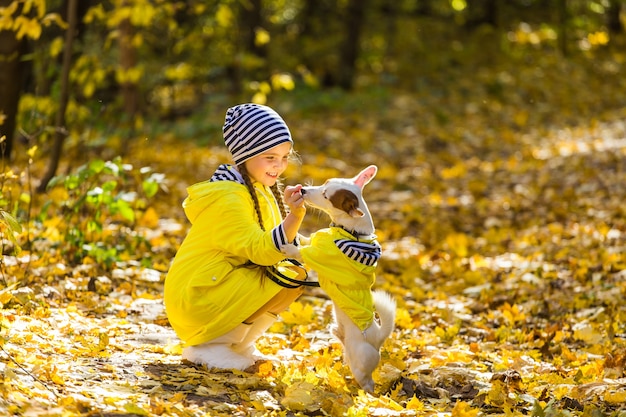 Niña con perro al aire libre. Niño con mascota en otoño. Cachorro de Jack Russell Terrier.