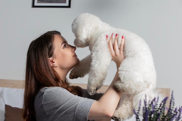 Una niña con un perro bichón juega en casa Dueño con un lindo perro