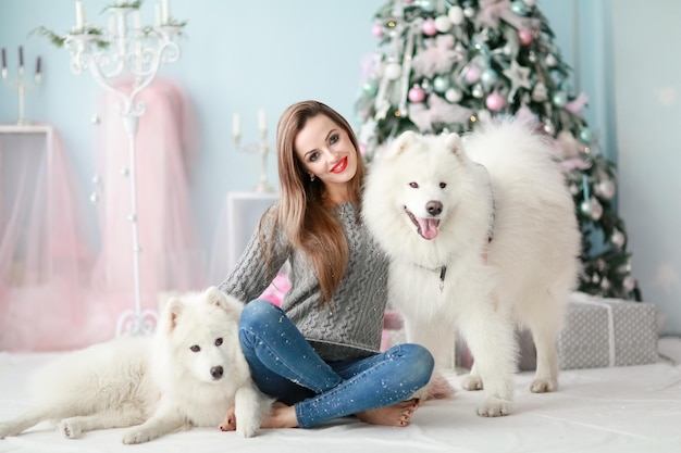 Una niña con un perro cerca del árbol de Navidad.