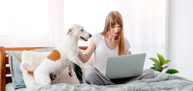 Niña, con, perro, y, computador portatil, en la cama