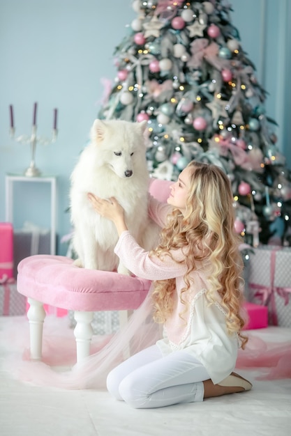 Una niña y un perro en un estudio fotográfico de Año Nuevo decorado en suaves tonos rosa pastel.