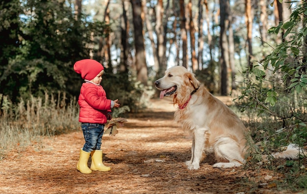 Niña con perro golden retriever en el bosque