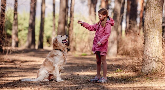 Niña con perro golden retriever en el bosque