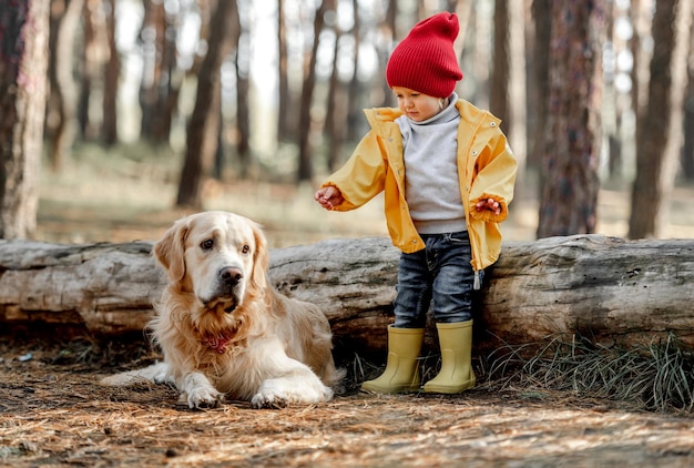 Niña con perro golden retriever en el bosque