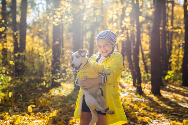 Niña con un perro jack russell terrier en el parque de otoño