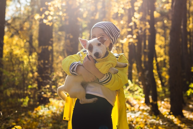 Niña con un perro jack russell terrier en el parque de otoño