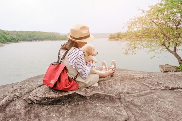 Foto niña con perro sentada en una roca en la orilla del lago