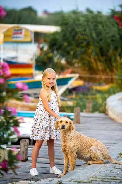 Una niña con un perro en el terraplén junto al río con un vestido blanco en la ciudad de Dalyan. pavo