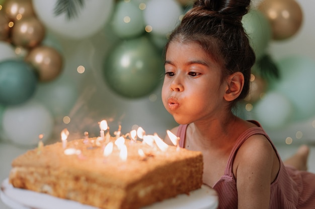 Niña pide deseo y sopla las velas de la tarta de cumpleaños niña celebrando su cumpleaños