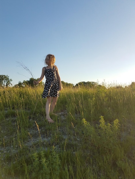 Foto niña de pie en el campo contra el cielo despejado