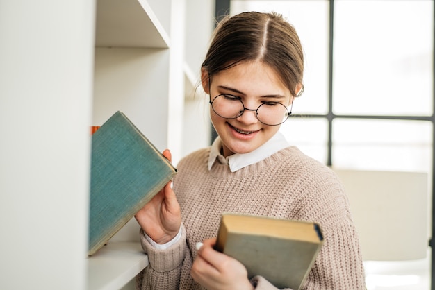 Niña de pie cerca de la estantería en la biblioteca