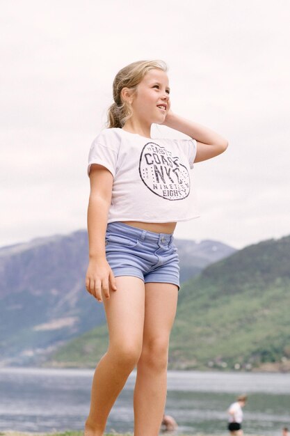 Foto niña de pie contra el mar y el cielo