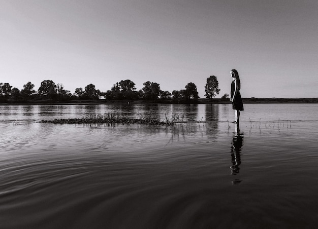 Niña de pie en el lago contra el cielo