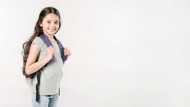 Niña de pie con mochila en estudio