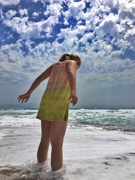 Foto niña de pie en la orilla de la playa