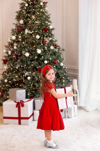 Niña de pie con presente en el salón en Navidad