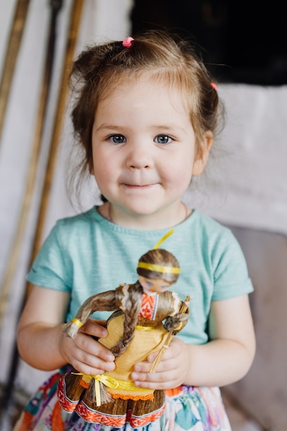 Foto la niña está de pie y sostiene una muñeca.