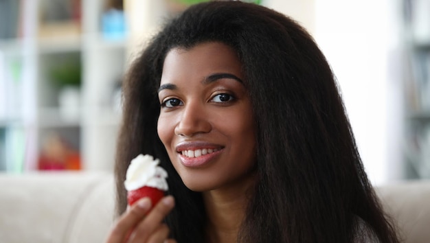 Niña de piel oscura sostiene fresas con crema