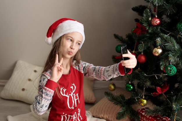 una niña en pijama de año nuevo la niña mira el teléfono