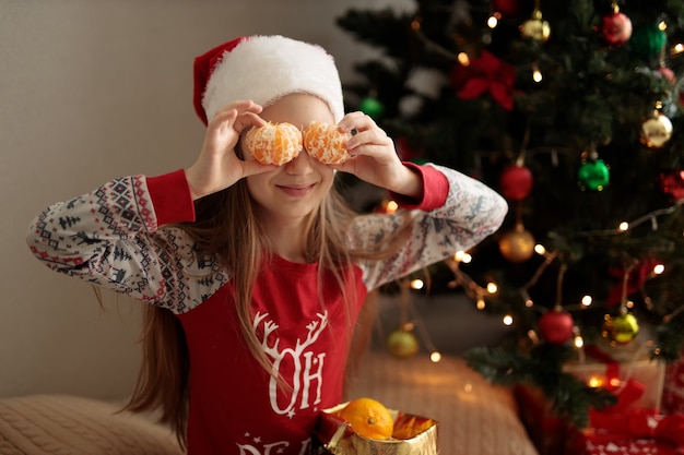 una niña en pijama de Año Nuevo la niña tiene naranjas en lugar de ojos