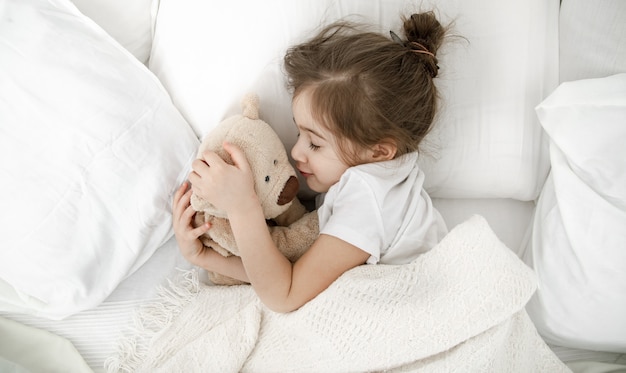 Niña en pijama ligero en la cama de cerca.