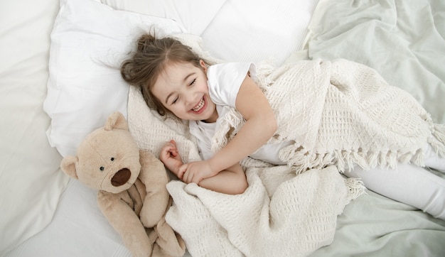 Niña en pijama ligero en la cama de cerca.